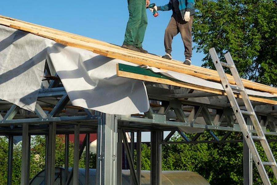 Des artisans travaillent sur une structure métallique robuste afin de modifier sa charpente pour intégrer des panneaux solaires en toiture sans risquer l'affaissement.
