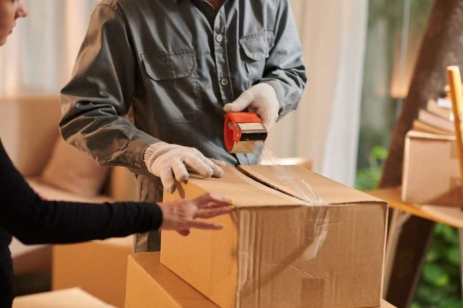 Professionnel utilisant du ruban adhésif pour sécuriser vos effets personnels dans un carton de déménagement.