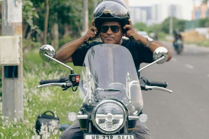 Un motard ajuste son casque derrière le pare-brise de sa moto pour choisir sa bulle moto idéale.